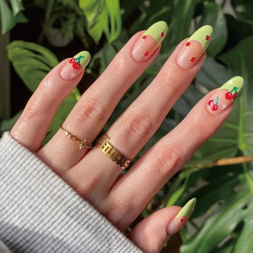 StarNagel Stiletto Nägel French Maniküre mit grünen Rändern, roten Diamanten und kleinen Kirschen